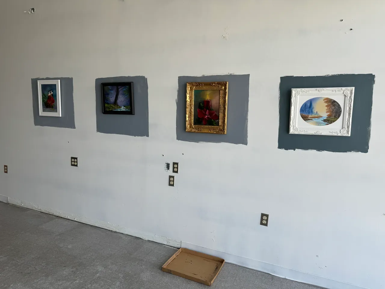 Four framed paintings on a gallery wall.