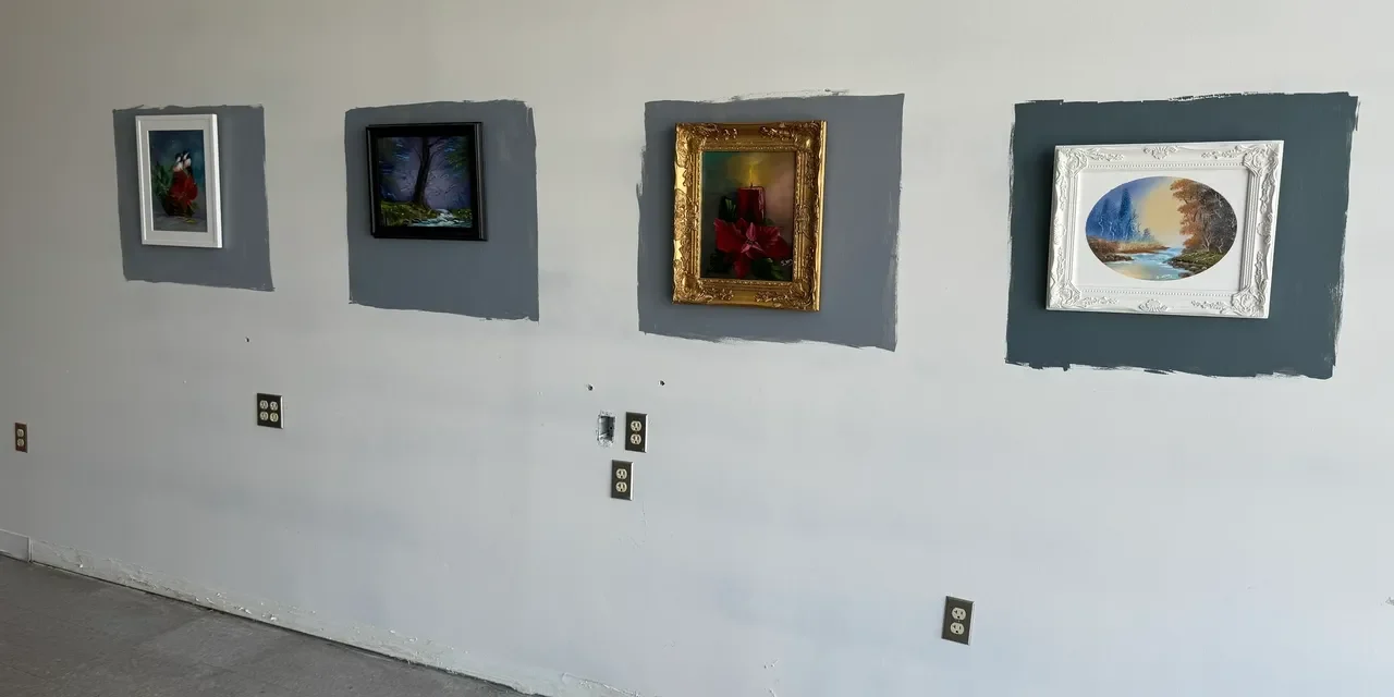 Four framed paintings on a gallery wall.